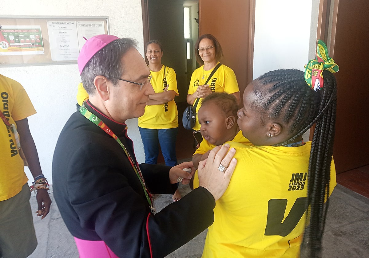 Monseñor saluda a una participante en la JMJ, que va acompañada de su hijo pequeño