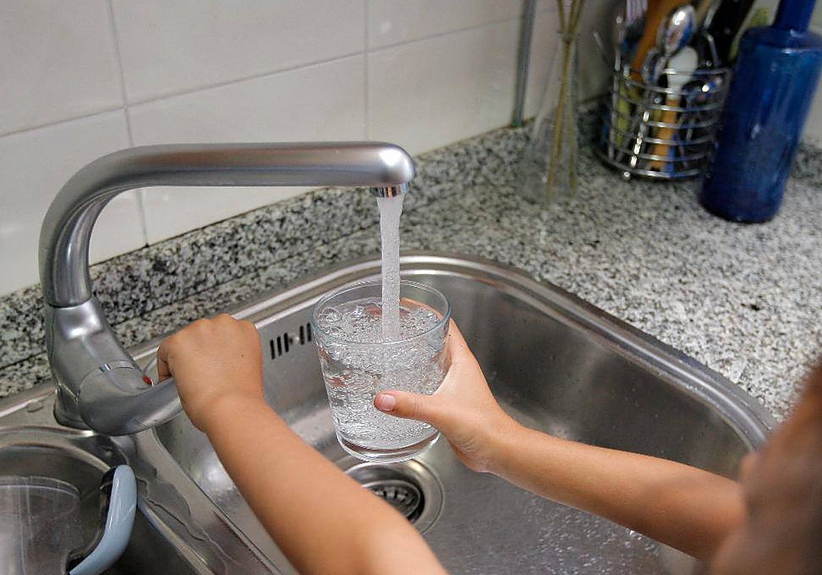 Una persona llena un vaso de agua de un grifo