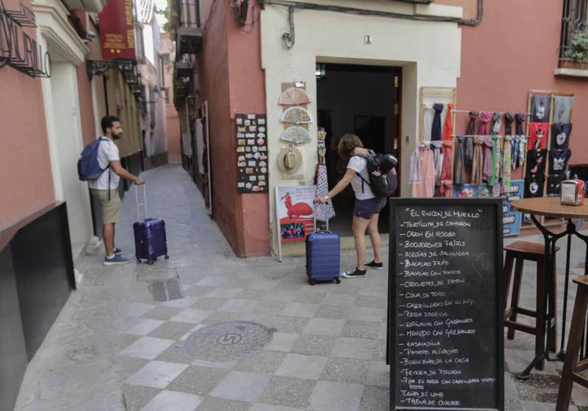 Dos turistas con maletas en el Barrio de Santa Cruz