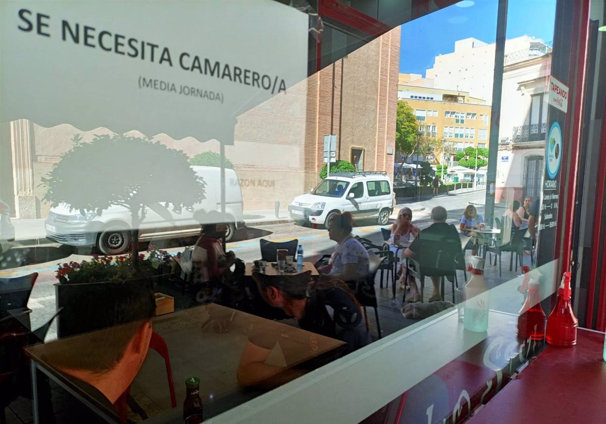 Cartel de 'Se busca camarero' en un bar con terraza