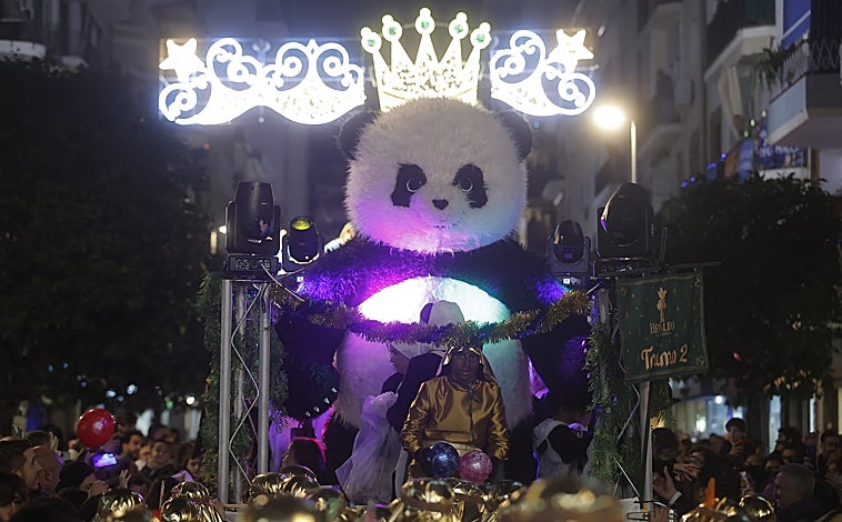 Imagen principal - La carroza El Panda, incluida en el cortejo que cerraba (abajo) el Heraldo a camello en un barrio entregado a la celebración 