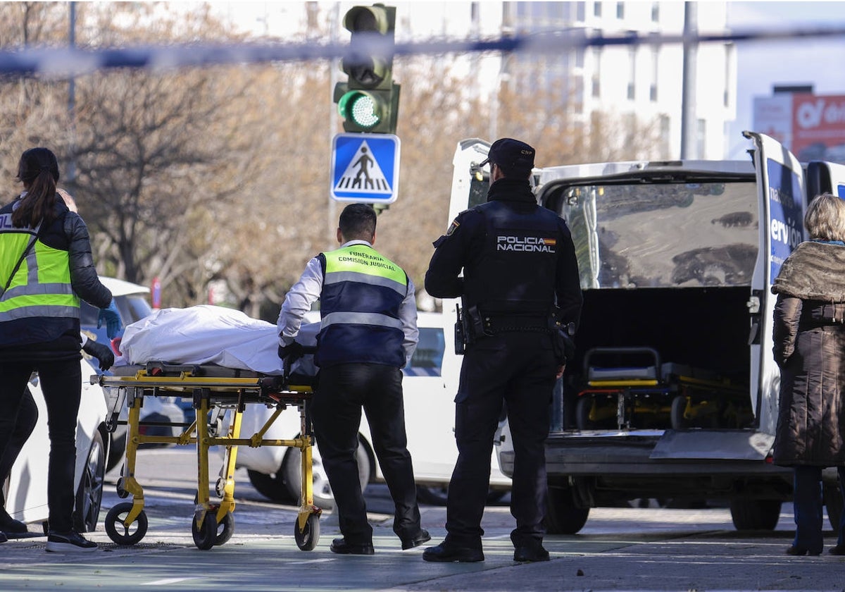 Los operarios de la funeraria trasladando el cadáver a la furgoneta ayer por la mañana en el lugar del crimen