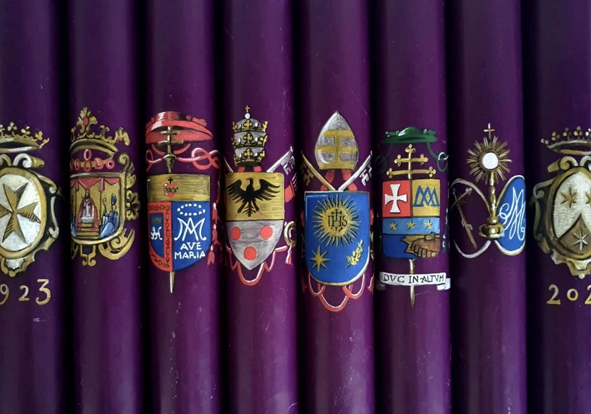 Imagen de los cirios del Señor de las Penas con los escudos con distintos escudos conmemorativos