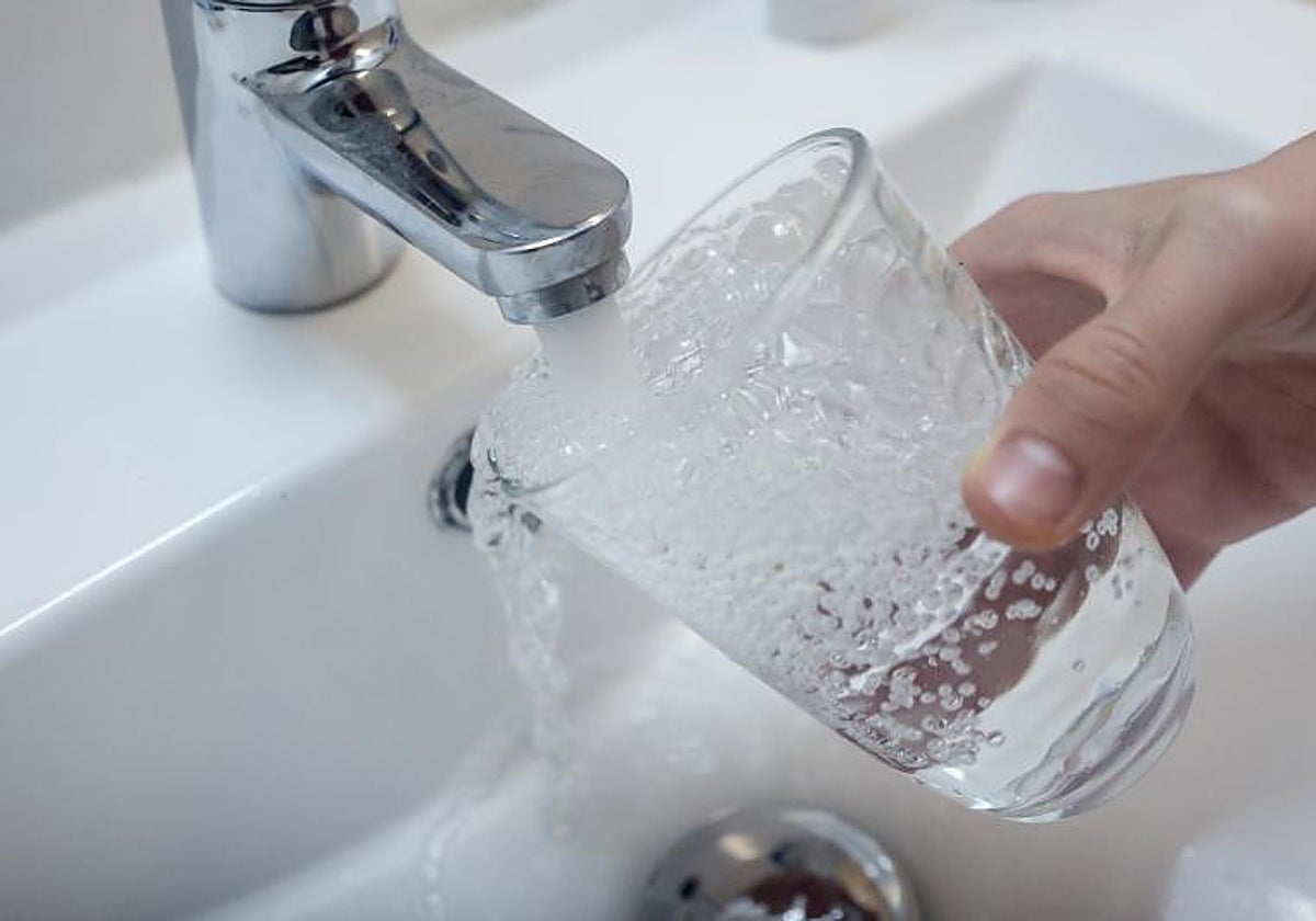 Un ciudadano llena un vaso de agua en su casa