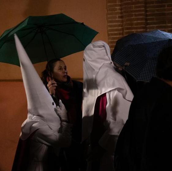 Dos nazarenos de las Siete Palabras, entre paraguas por la lluvia, este Miércoles Santo de la Semana Santa de Sevilla