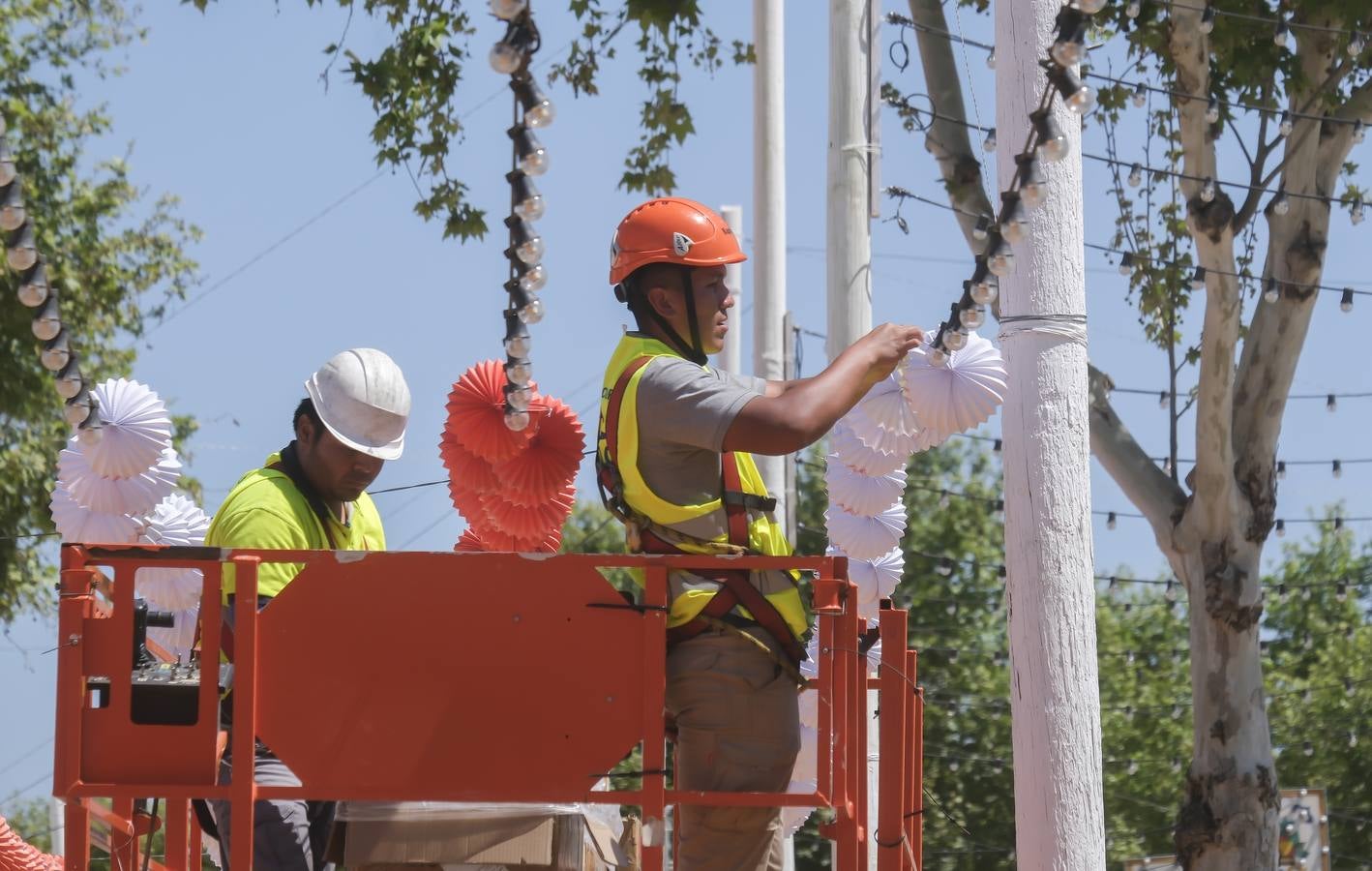 Operarios colocan los farolillos que se estropearon durante la lluvia de esta semana