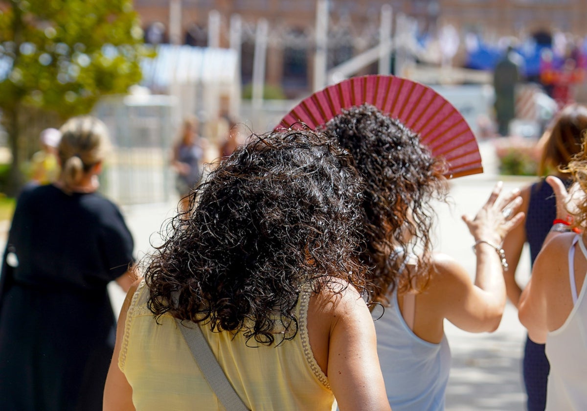 Dos mujeres con un abanicos pasean por el Parque de María Luisa un día de calor veraniego en Sevilla