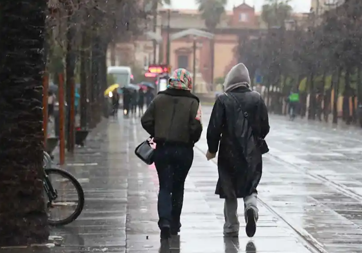Imagen de archivo de dos personas caminando bajo la lluvia por la calle San Fernando
