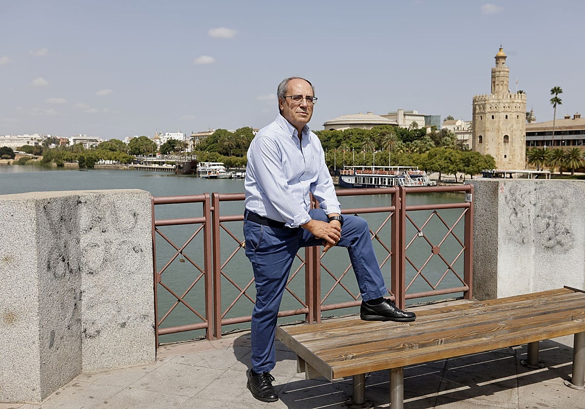 José María Barrera apoya su pie izquierdo sobre un banco del Puente de San Telmo, con la Torre del Oro al fondo