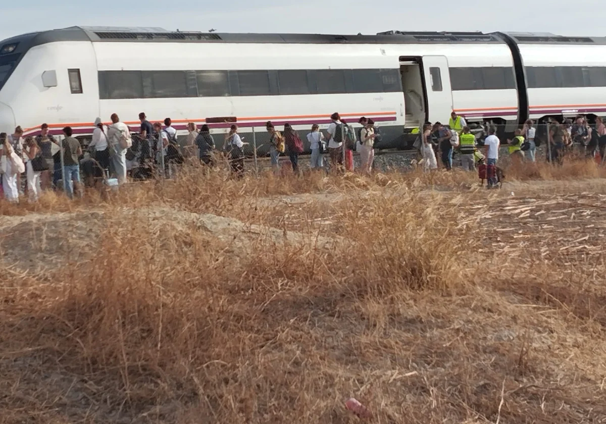 Los viajeros saliendo del tren en el lugar donde se ha quedado parado