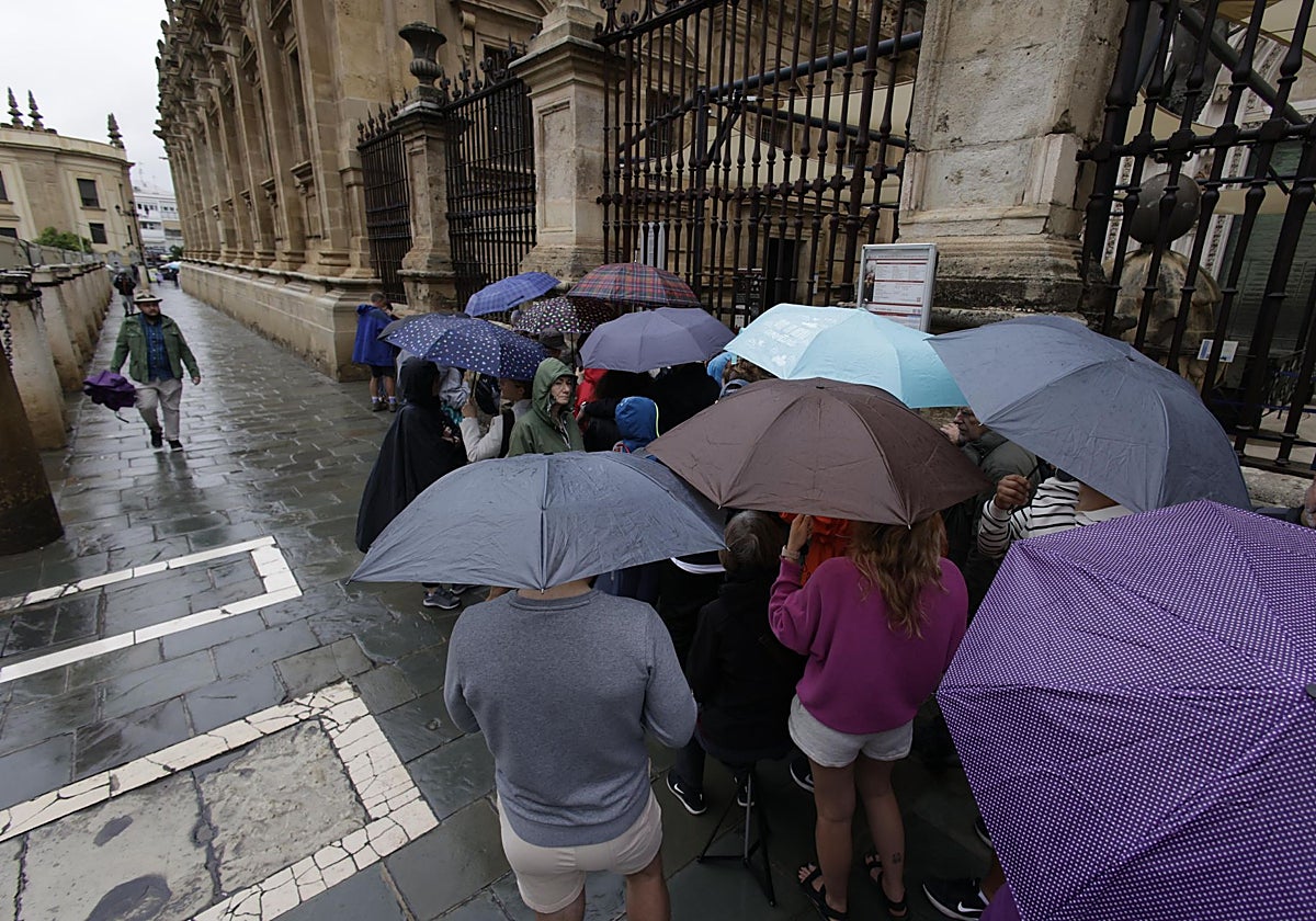 Visitantes bajo la lluvia a las puertas de la Catedral de Sevilla