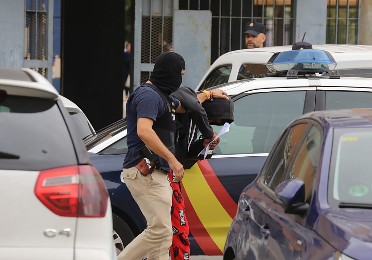 Un agente de la Policía Nacional con unos de los detenidos este viernes en las Tres Mil Viviendas