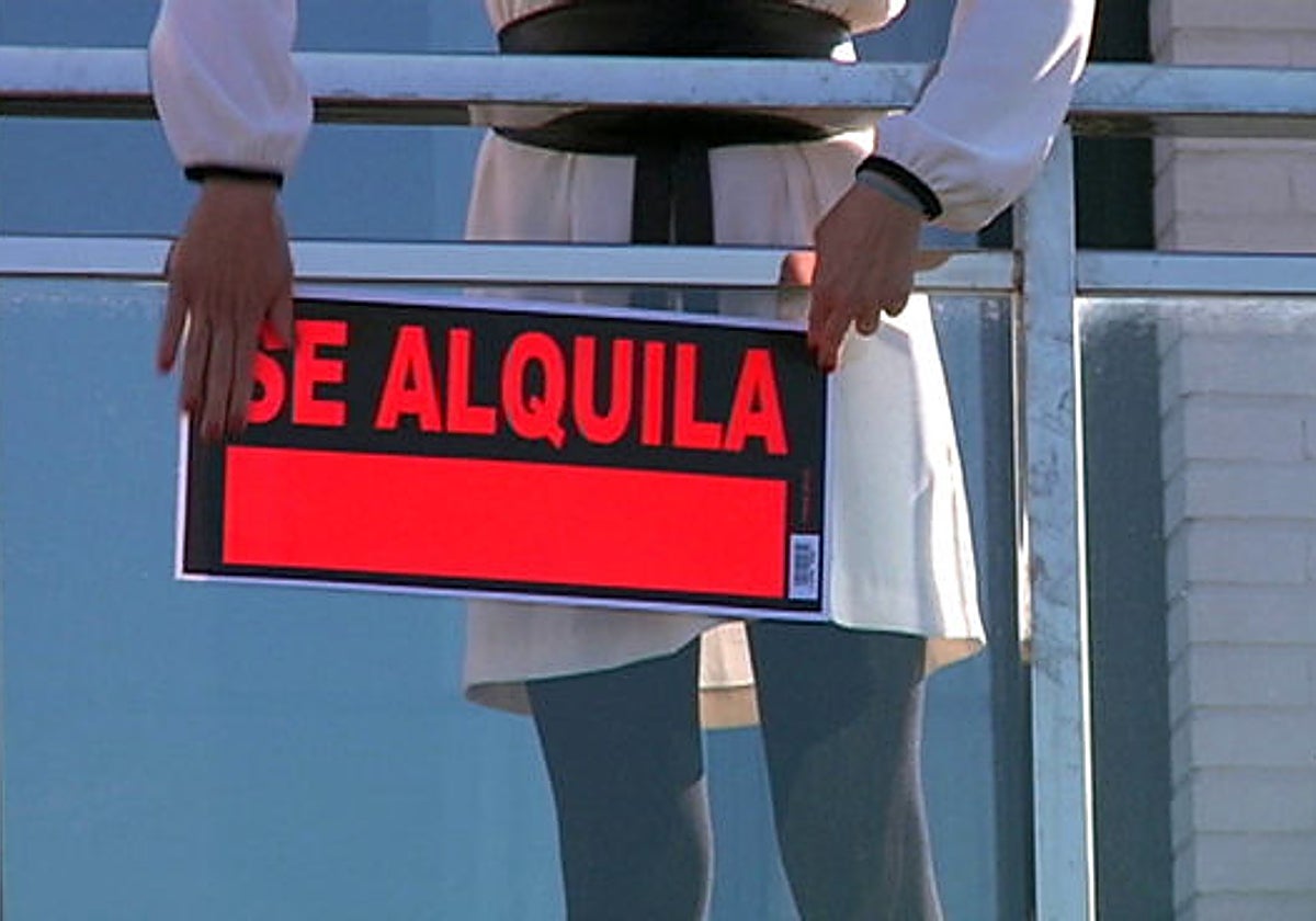 Imagen de archivo de una persona colocando un cartel de «Se alquila» en una vivienda