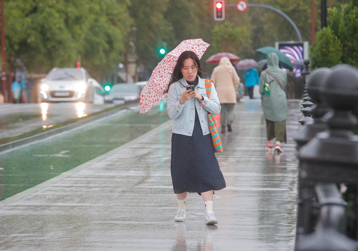 Una turista por el puente de Triana en una jornada de lluvia