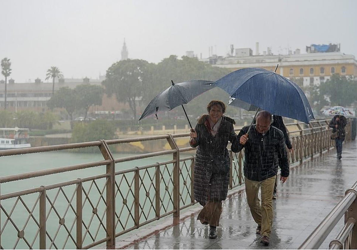 Personas caminando bajo la lluvia por el Puente de Los Remedios