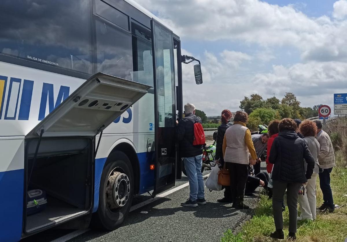 Un grupo de personas que viajaban en el autobús rodean al conductor para comprobar su estado, minutos después del incidente