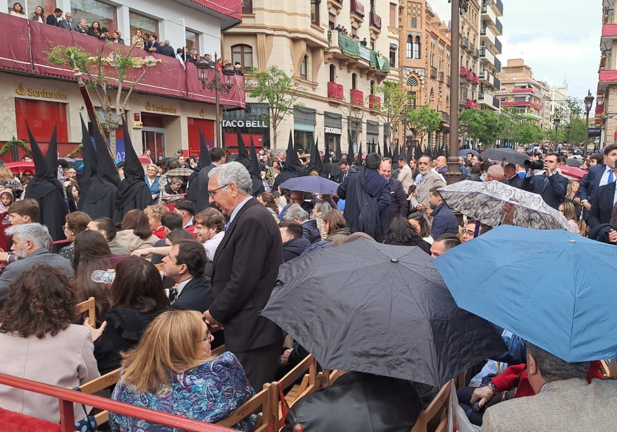Personas protegiéndose con paraguas en la Campana ante la llovizna de este Miércoles Santo