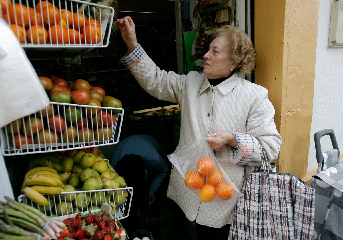 Una clienta compra frutas y verduras en un comercio local