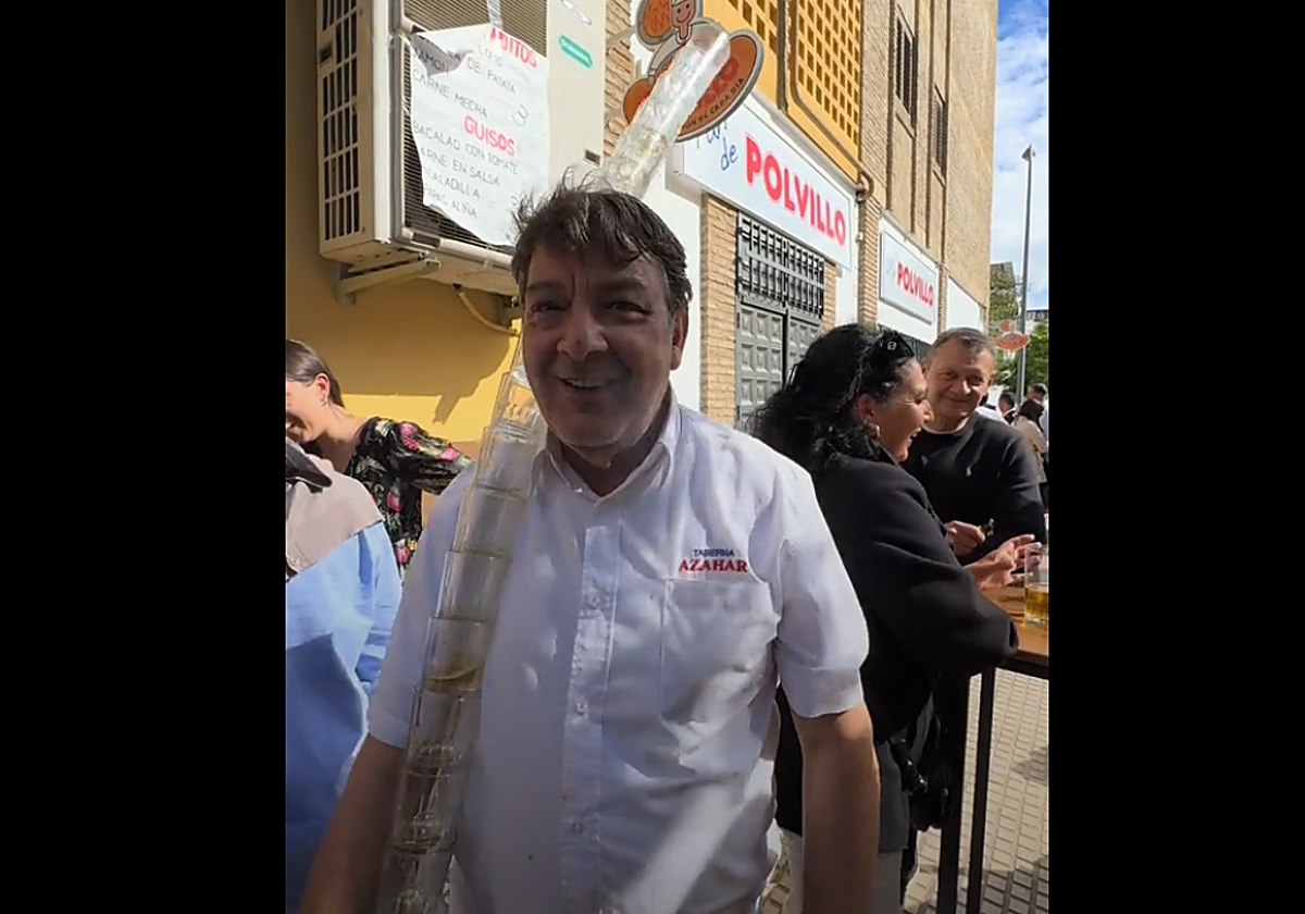Juan Oliveira, tabernero y dueño del bar, recogiendo los vasos de cerveza a la manera tradicional