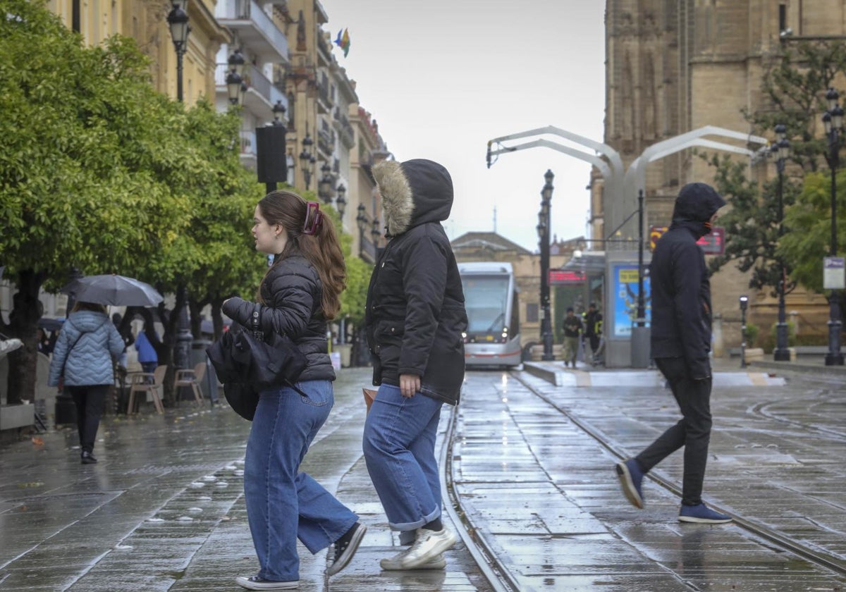 Turistas en la avenida de la Constitución bajo la lluvia