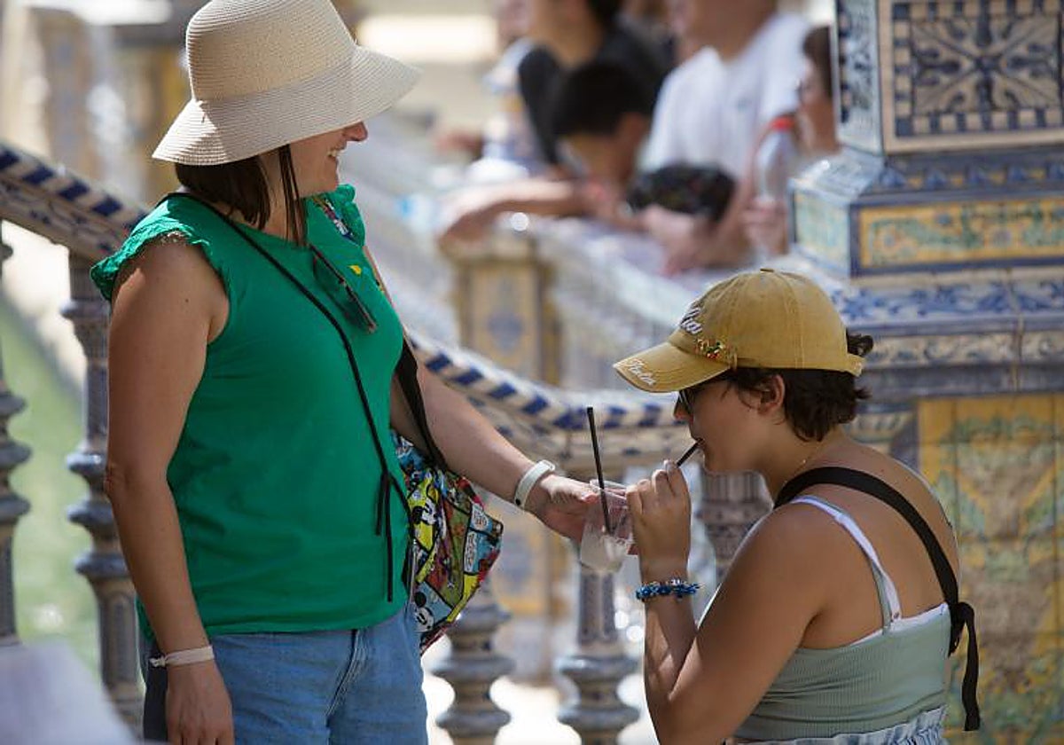 Dos personas se refrescan en la Plaza de España debido a las altas temperaturas
