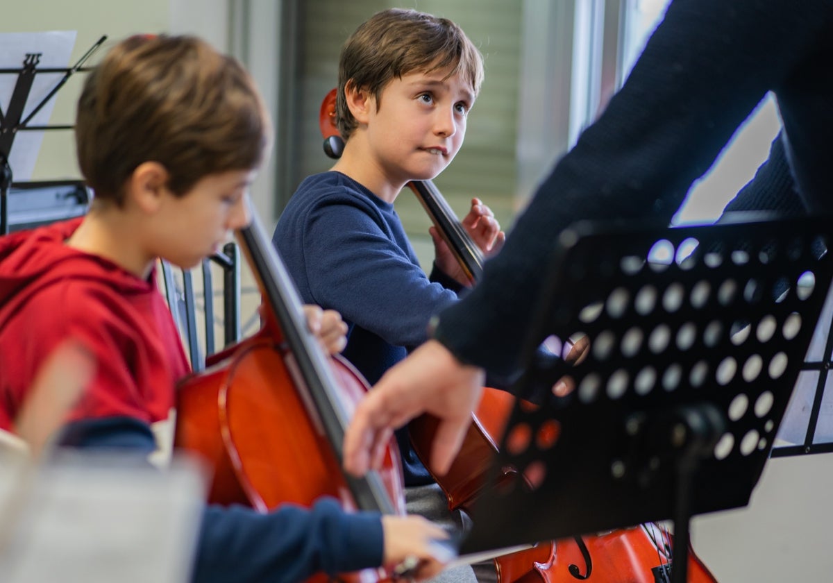 Dos alumnos del colegio San Francisco de Paula recibiendo clases de violonchelo