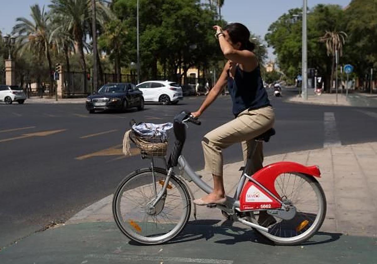Una joven pasea con su bicicleta en Sevilla con calor