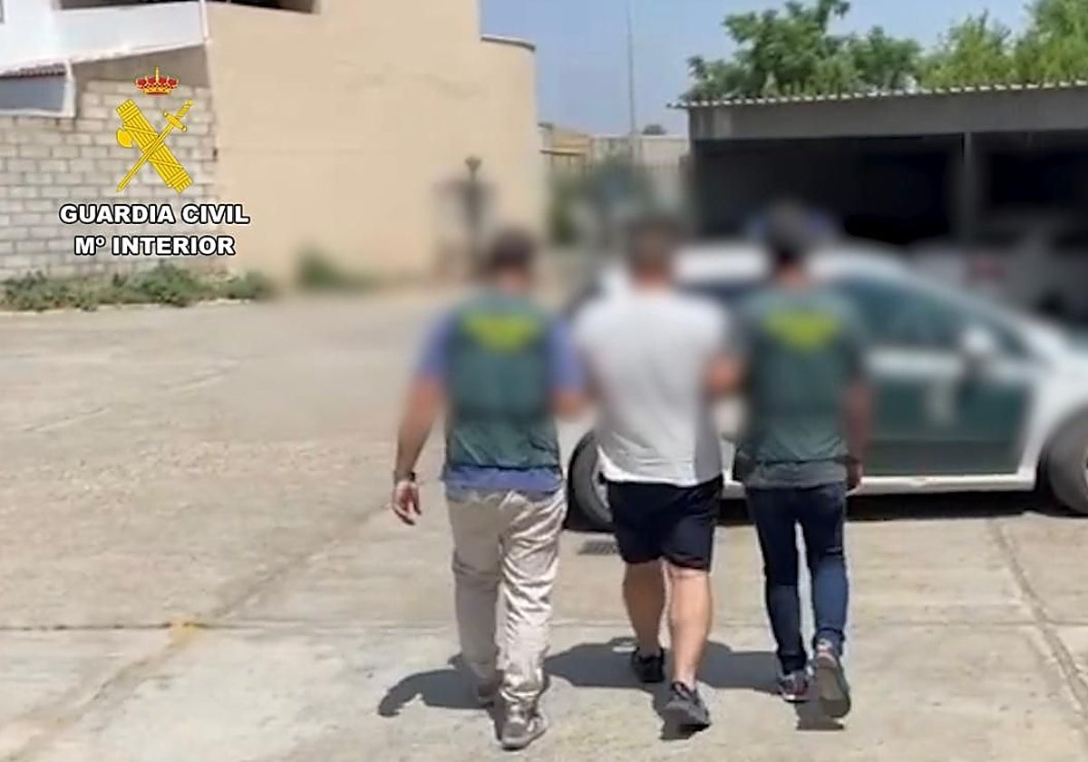 Dos agentes de la Guardia Civil custodian a uno de los detenidos por el robo en Olivares