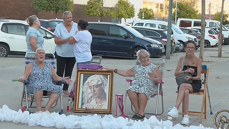 Huchi y María del Carmen, a la izquierda y derecha del cuadro, enseñan el rostro de la Esperanza de Triana en compañía de otras vecinas de Las Letanías que prepararon toda la decoración de la barriada