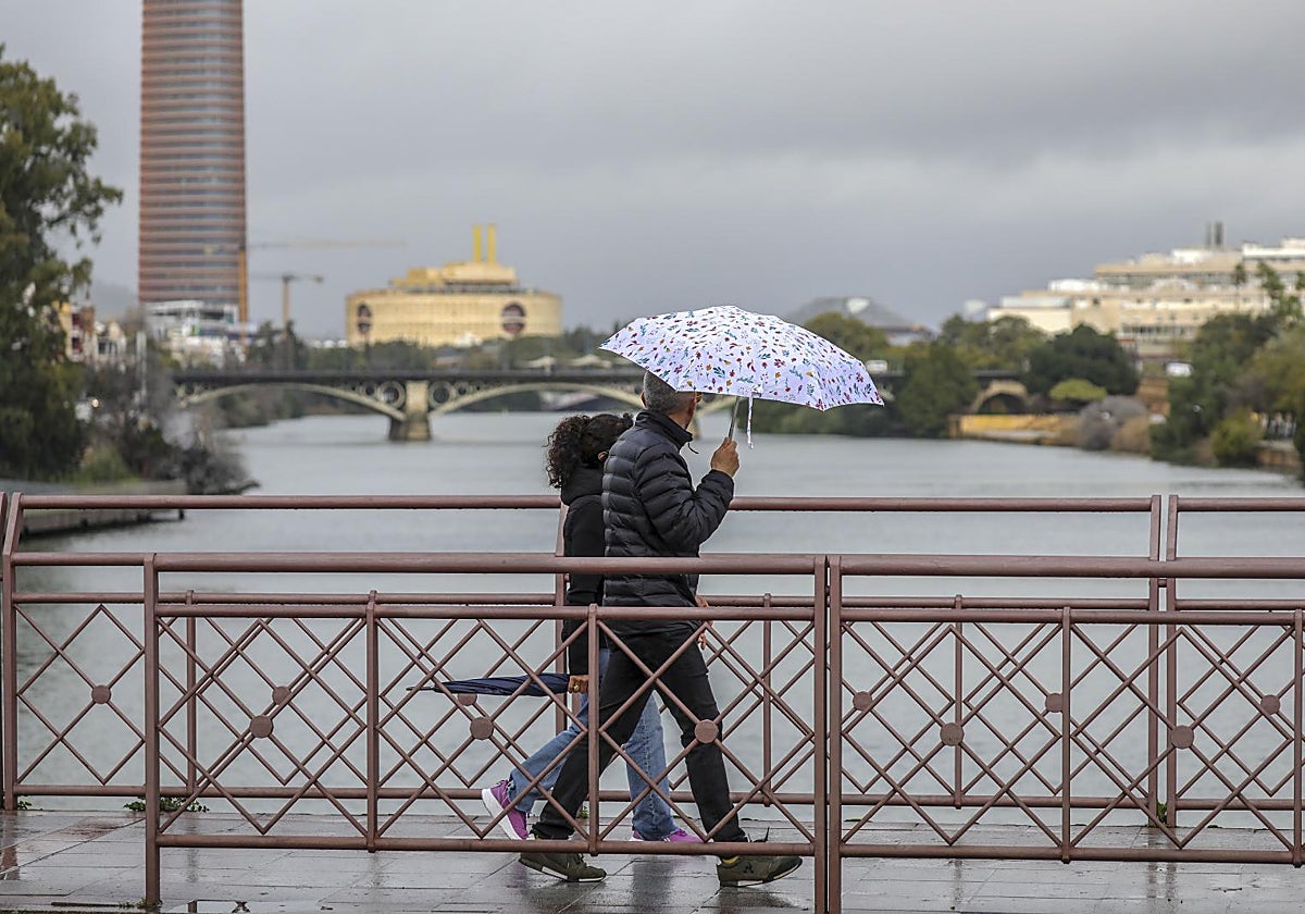 Viandantes por el puente de San Telmo bajo la lluvia