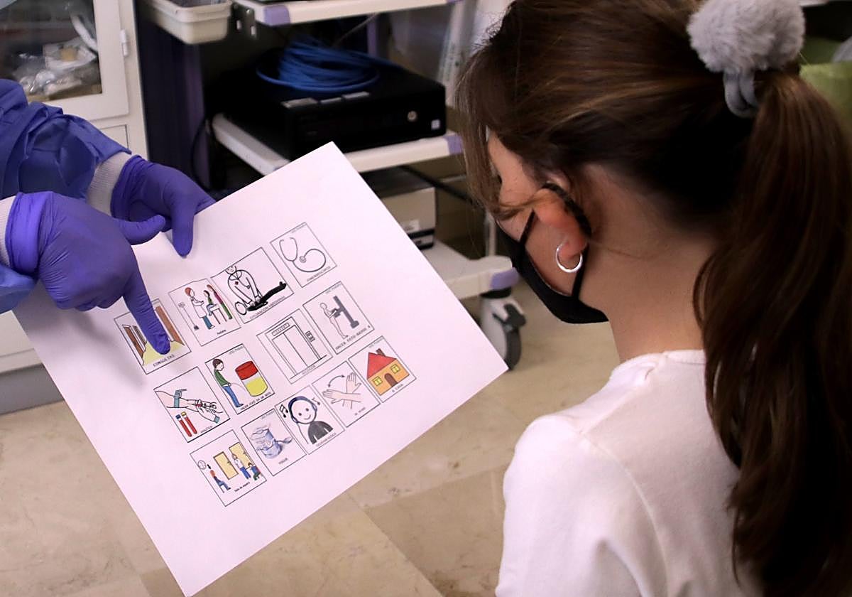 Una niña con TEA recibe la información del médico mediante pictogramas