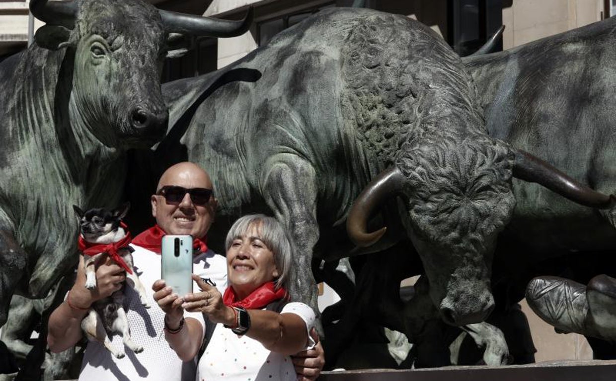 Dos turistas de Valencia junto a su mascota se hacen un selfie junto al monumento al encierro con la ropa típica de los sanfermines
