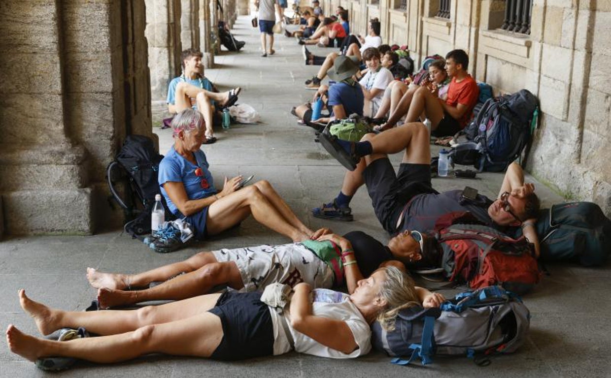 Peregrinos descansan en los bajos del Palacio de Raxoy, en la plaza del Obradoiro, para escapar del calor