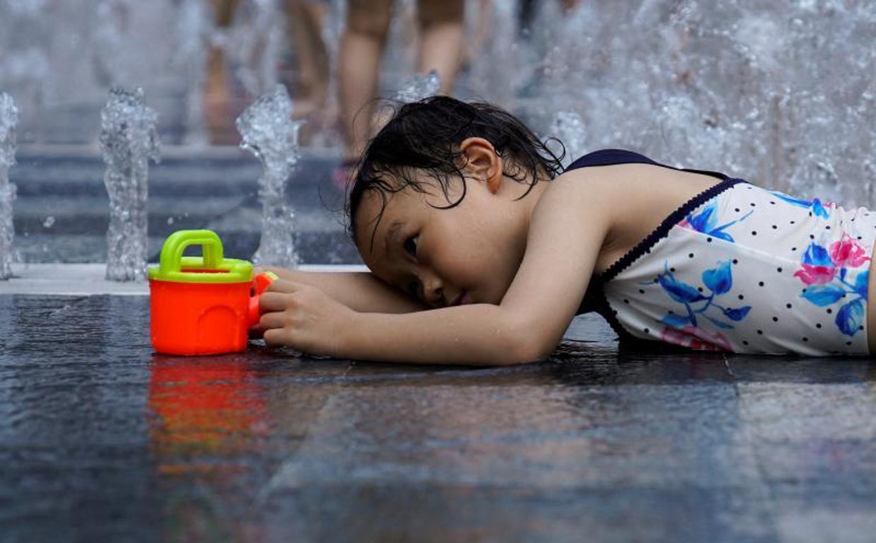 Una niña juega con el agua de una fuente para combatir  las altas temperaturas en Shanghai (China)