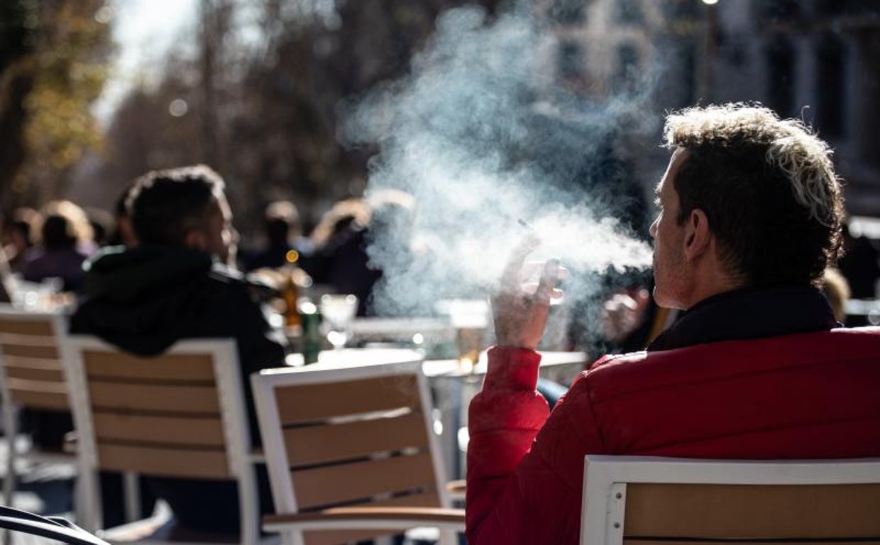 Un joven fuma en una terraza