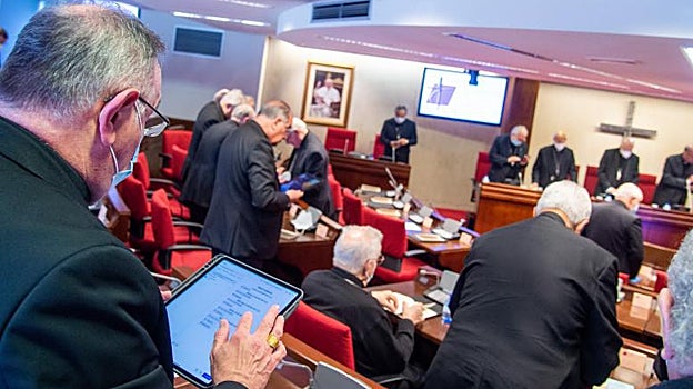 Un obispo busca la oración en  el iPad al comienzo de una Plenaria