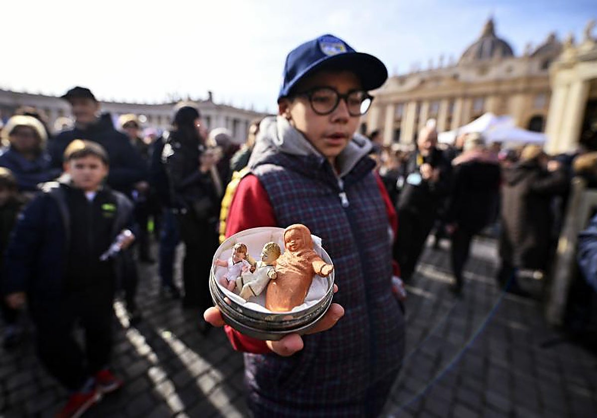 Un niño lleva su figura del Niño Jesús para que el Papa la bendiga