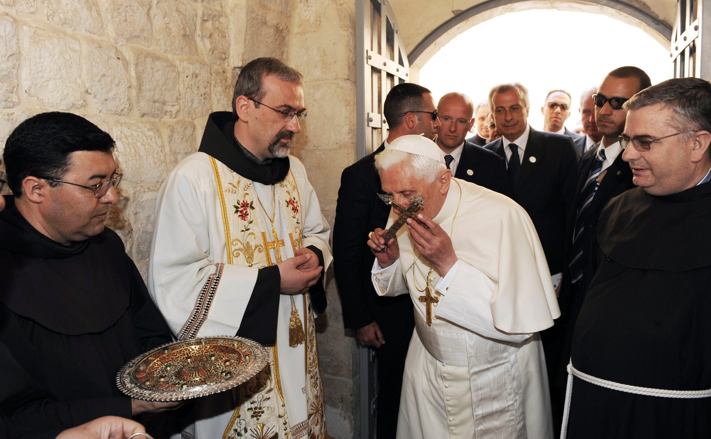 El Papa Benedicto XVI (C) besa una cruz durante su visita al Cenáculo, donde la tradición cristiana dice que Jesús asistió a la Última Cena, en el Monte Sión, en las afueras de las murallas de la Ciudad Vieja de Jerusalén, el 12 de mayo de 2009.