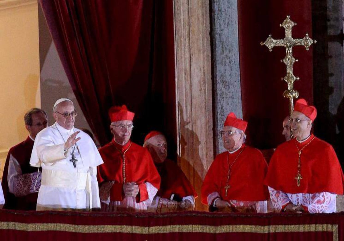 El Papa Francisco, rodeado por los cardenales, saluda a los fieles instantes después de su elección