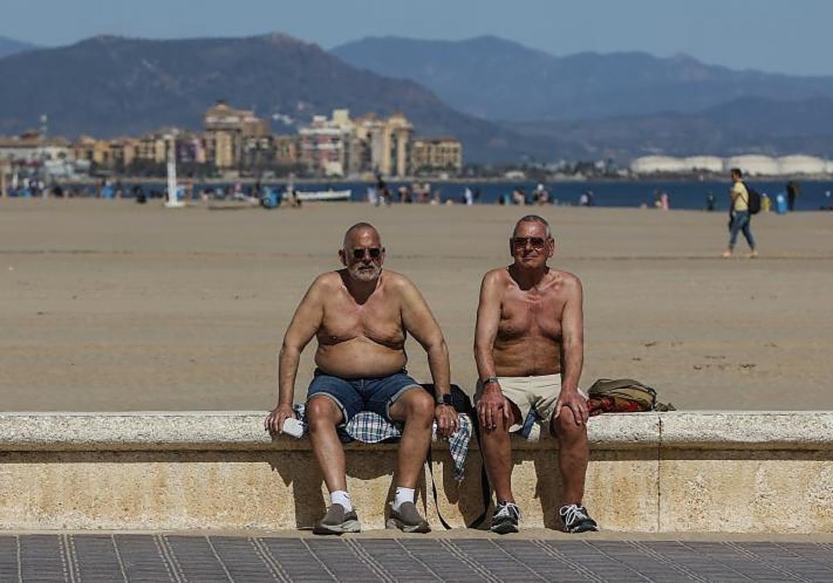 Dos hombres toman el sol en la playa de La Malvarrosa en Valencia