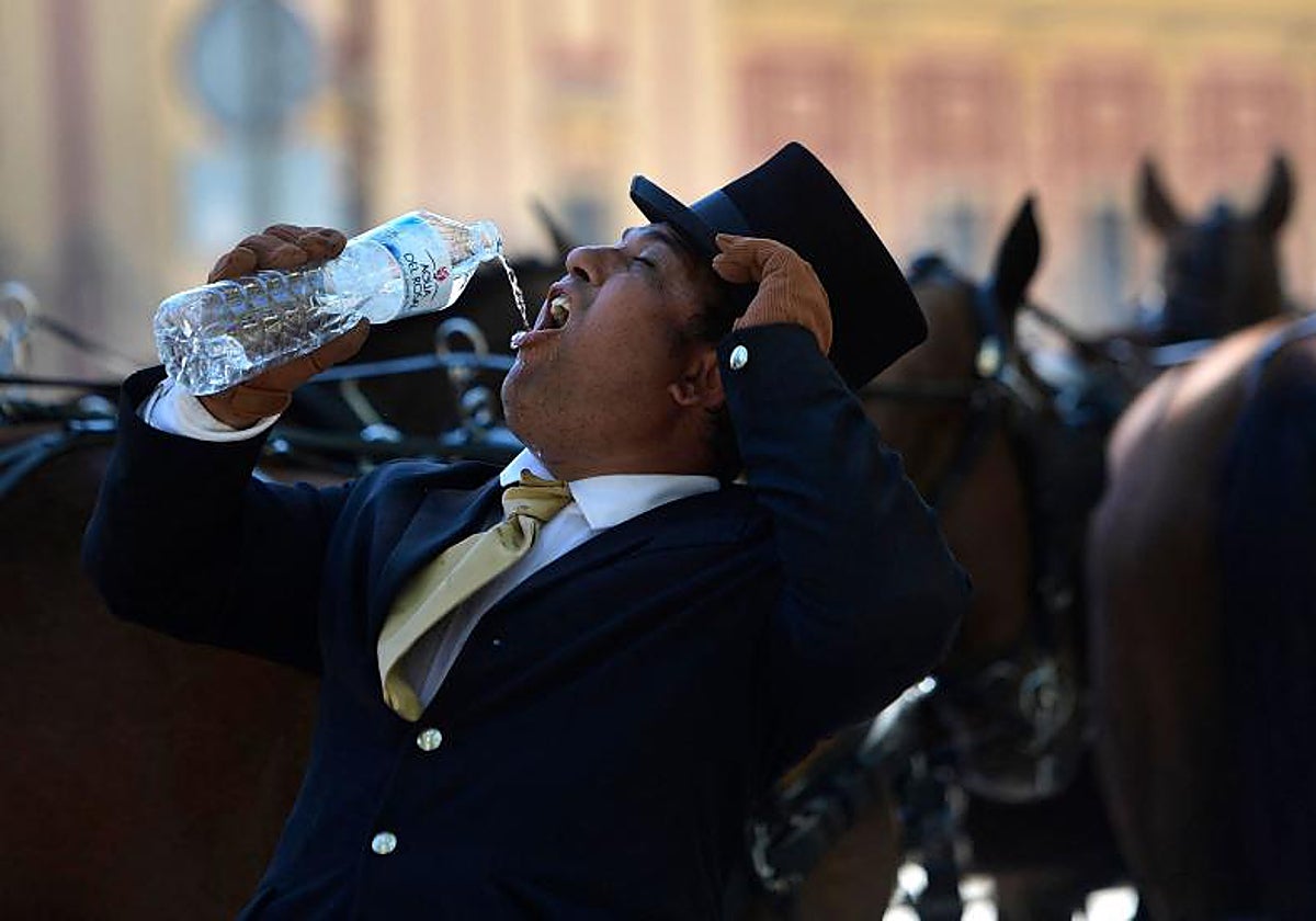 Un hombre se refresca en la feria de Sevilla