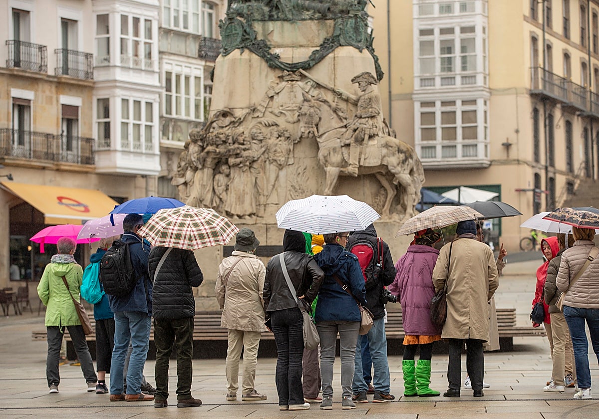 Un grupo de turistas se protege con paraguas de la lluvia en Vitoria