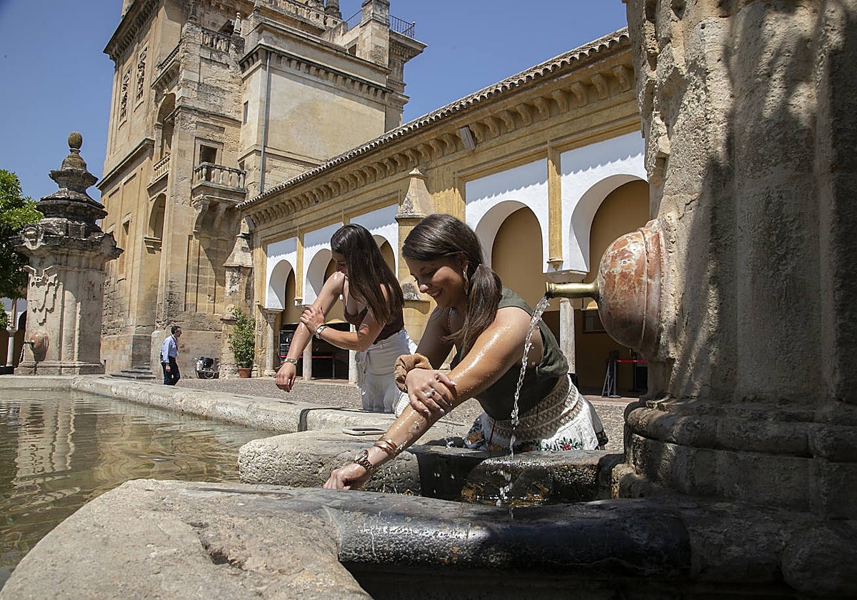 Dos jóvenes se refrescan en una fuente en Córdoba