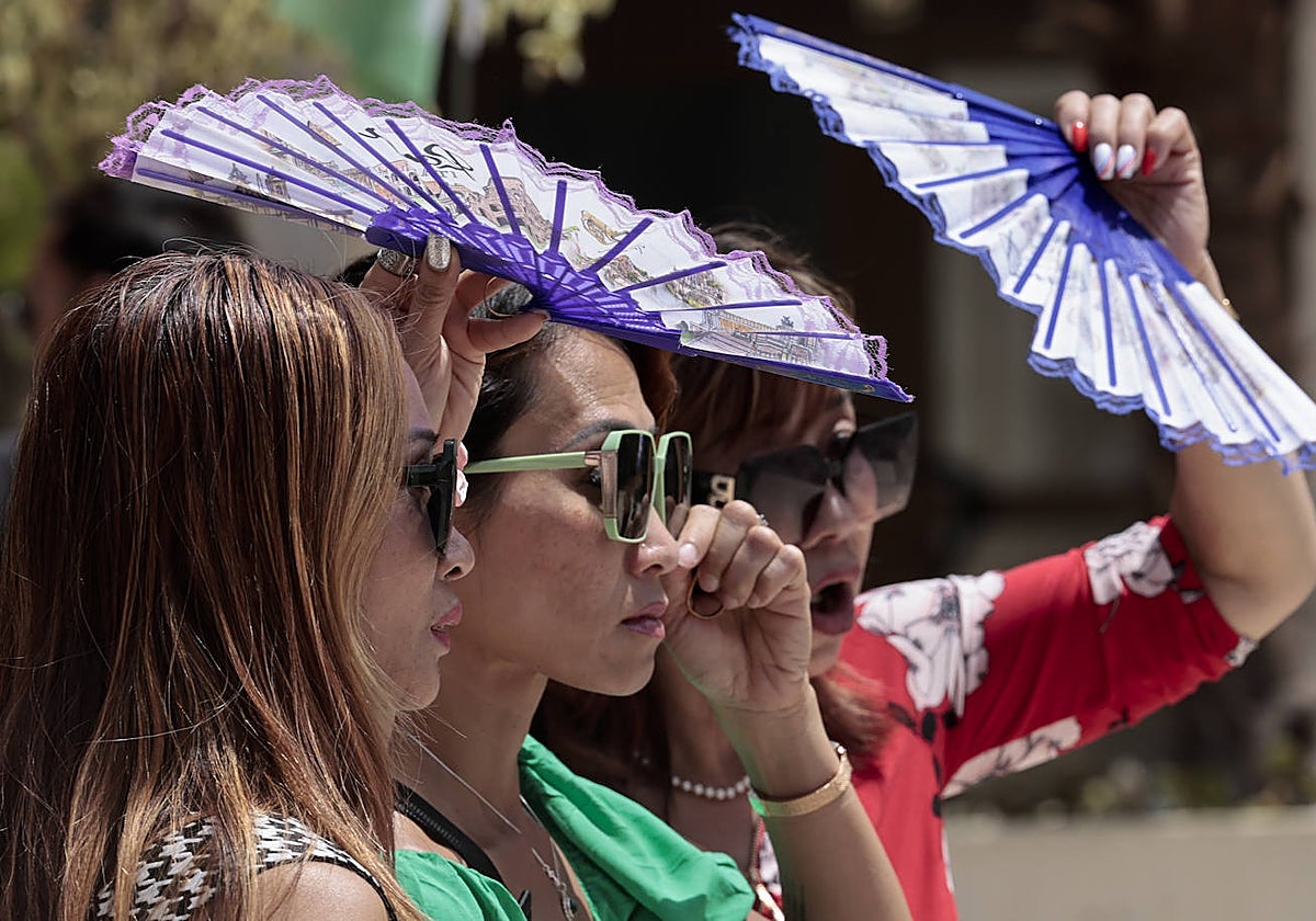 Tres turistas se protegen del calor con abanicos en Valencia