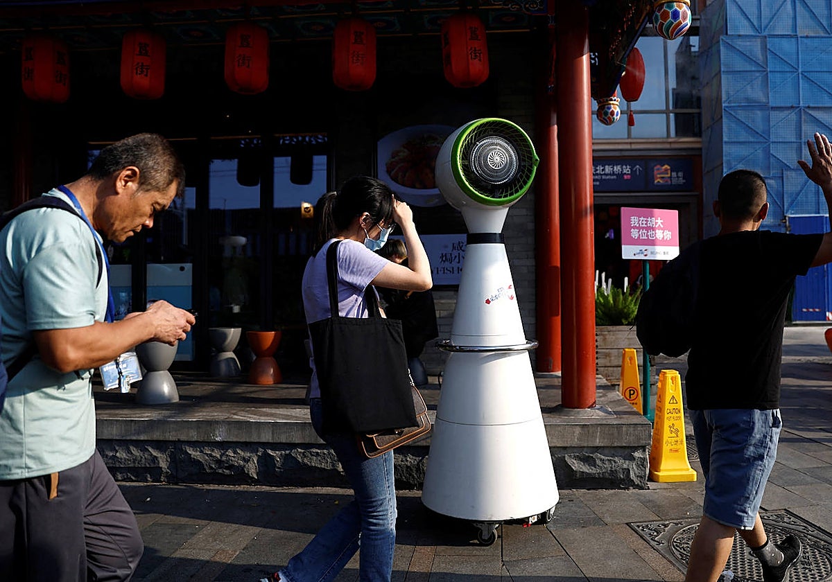 Varias personas pasan frente a un ventilador en plena ola de calor en Pekín