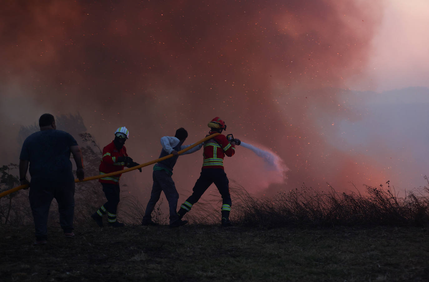 Un bombero con la ayuda de lugareños intentan extinguir un incendio forestal en Cascais, Portugal 