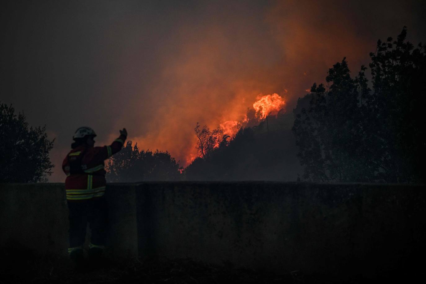 Un bombero observa la progresión de un incendio forestal mientras se acerca al pueblo de Zambujeiro