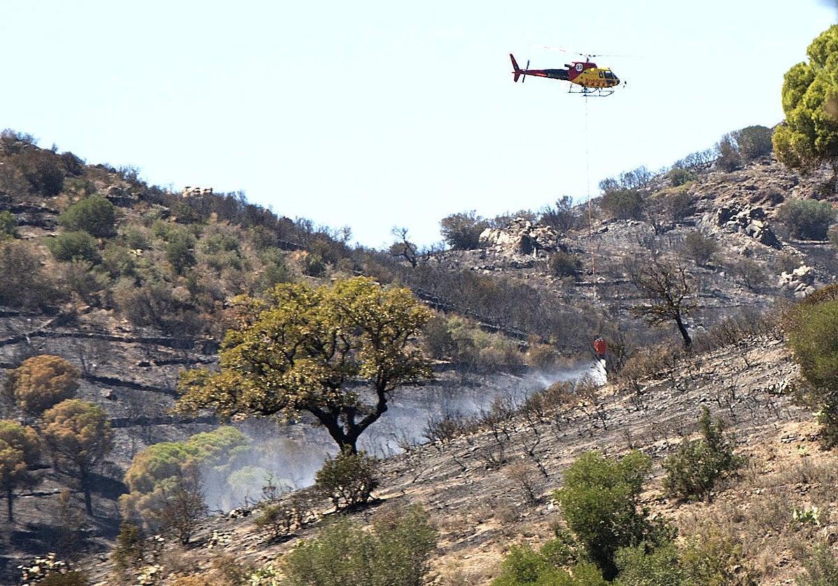 Un helicóptero trabaja en las labores de exinción de un incendio forestal en Colera