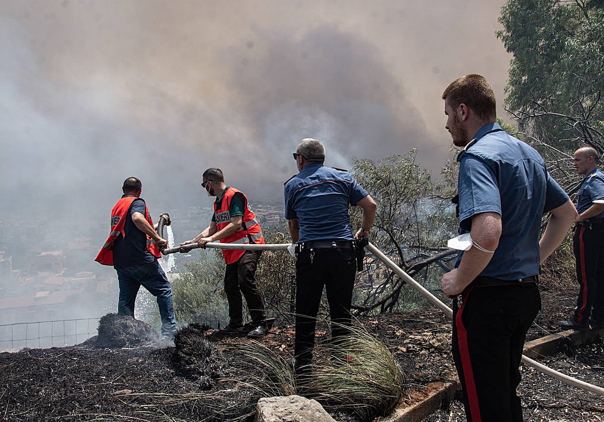 Agentes de Policía ayudan a los lugareños a apagar un fuego que se acercaba a las casas en Palermo, Sicilia