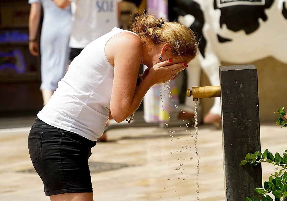 Una mujer se refresca en una fuente en Valencia
